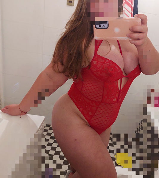 Hermosa escort con vestido de color rojo, foto de espejo en un baño