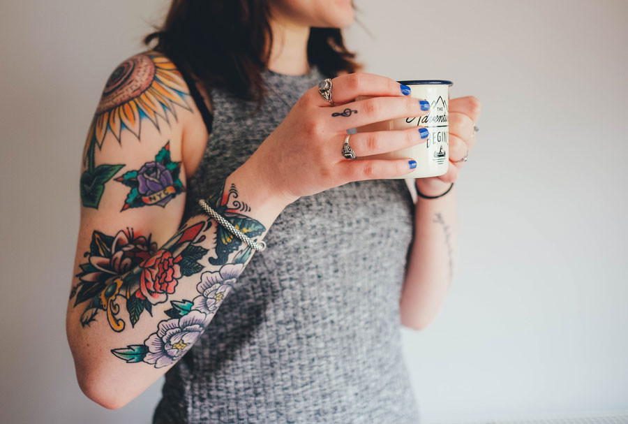 Mujer con tatuajes y una taza de cafe